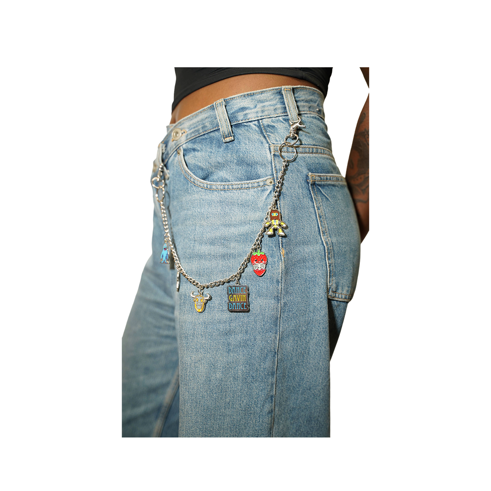 Close-up of a person wearing light blue denim jeans with a silver chain accessory draped over the back pocket, decorated with small charms including a strawberry, a small figure, 