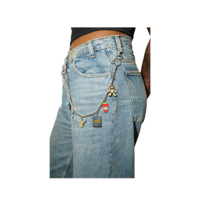 Close-up of a person wearing light blue denim jeans with a silver chain accessory draped over the back pocket, decorated with small charms including a strawberry, a small figure, 