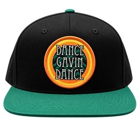 A structured snapback cap with a black crown, green flat brim, and a green button, featuring a circular embroidered patch on the front with the text 'DANCE GAVIN DANCE' in white with black outlines, set against a green background with yellow and orange concentric rings.