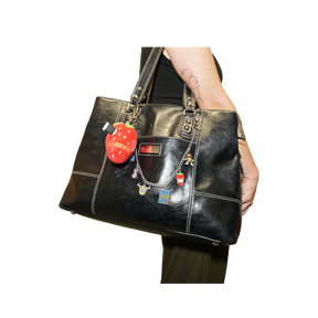 A black leather tote bag with silver-tone hardware and multiple charms, 